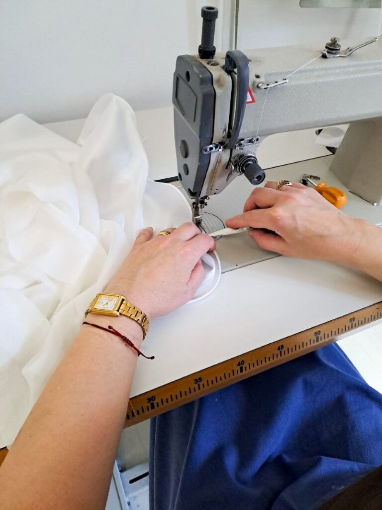 Ultima fase di cucitura dell'orlo di una gonna da sposa realizzata su misura