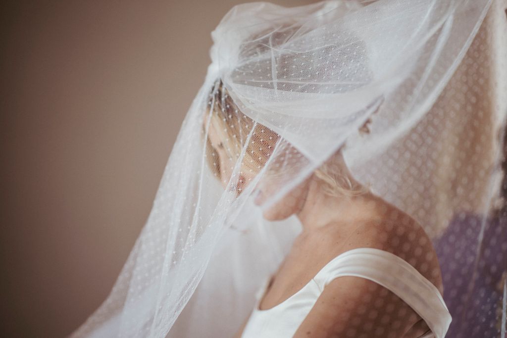 La mamma aiuta la sposa a indossare il velo di famiglia