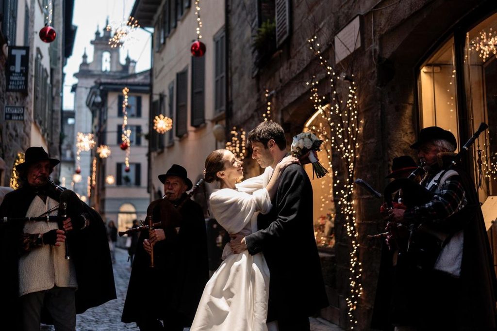 Marina in abito da sposa con gonna in mikado, maglia e stola in lana Loro Piana